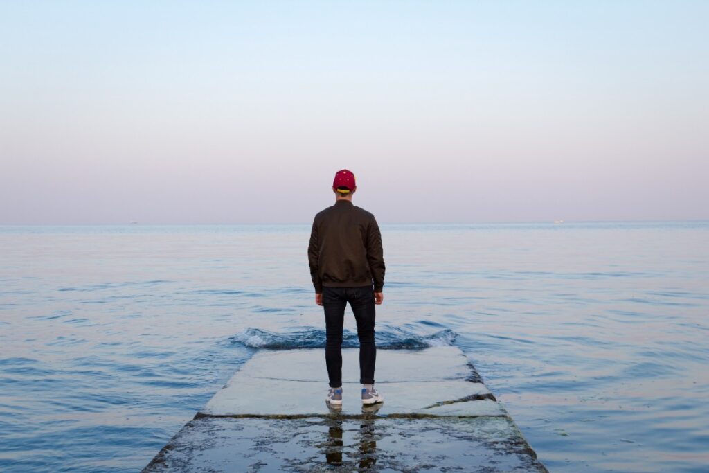 “man standing on concrete dock facing sea” by Nicholas Barbaros on Unsplash